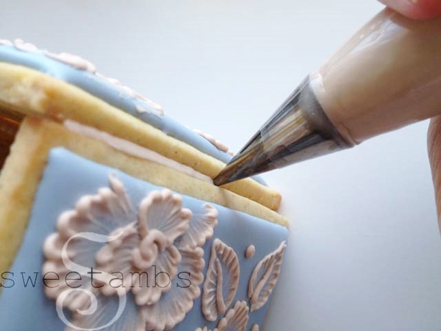 decorating tip filling the seam of the box with icing.