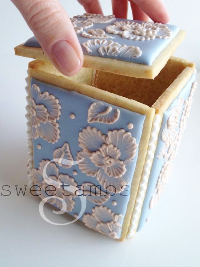 A hand placing the lid on top of the cookie box.