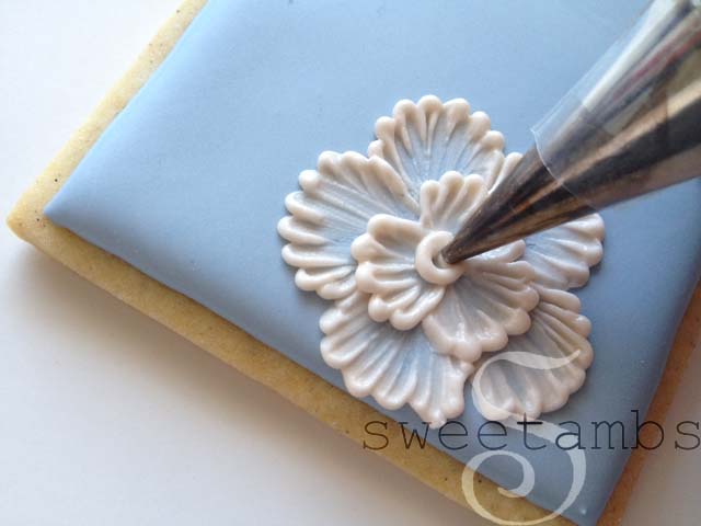 A decorating tip piping a swirl of icing in the middle of the flower 