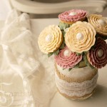 A mason jar wrapped in burlap and lace and filled with floral cookie pops