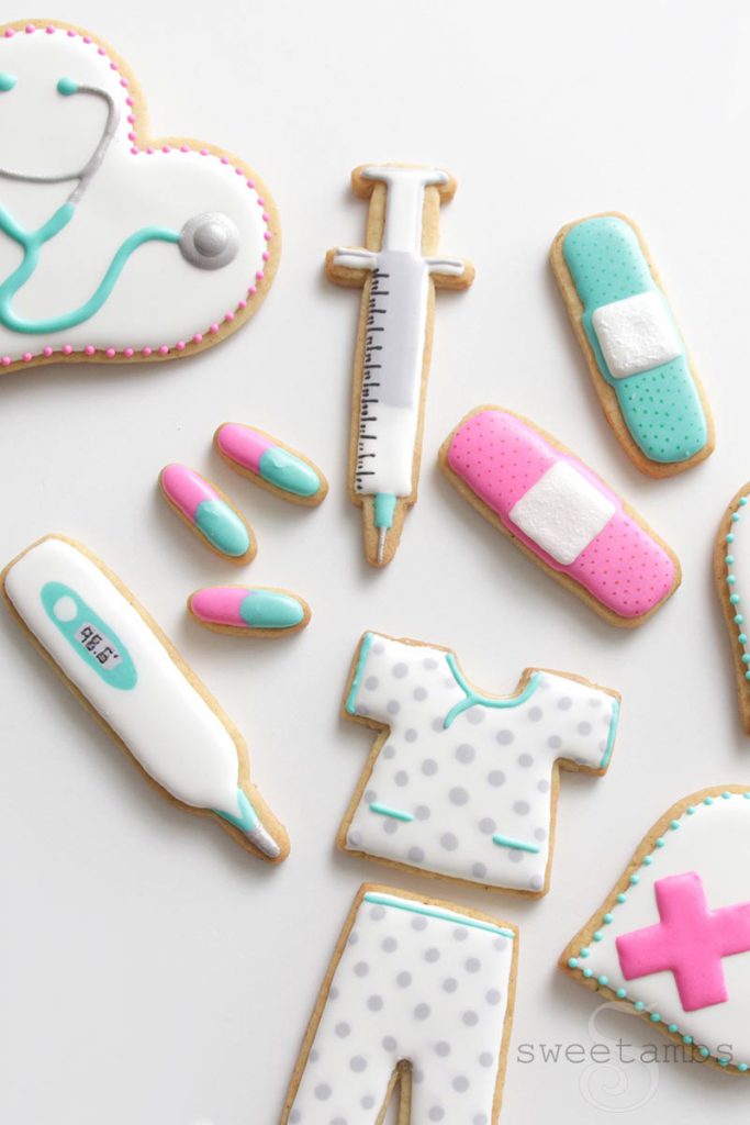 Cookies decorated to look like a syringe, a stethoscope, bandages, pills, a thermometer, and nurse scrubs.