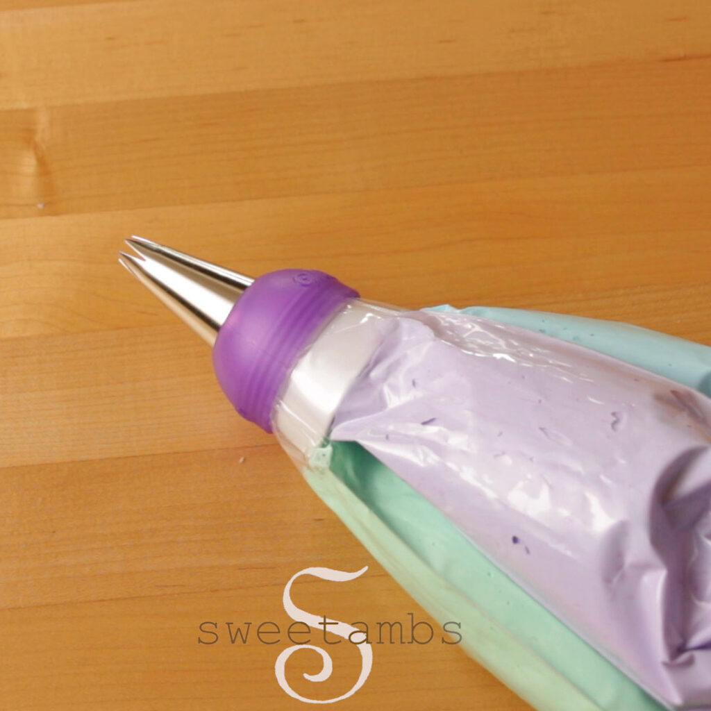 The assembled 3-color coupler with pastel green, purple, and blue meringue in the decorating bags. The coupler is fitted with a 1M star tip.
