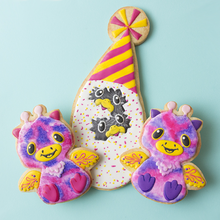 Cookies decorated to look like Hatchimals Surprise toys. The Hatchimals egg is wearing a party hat.