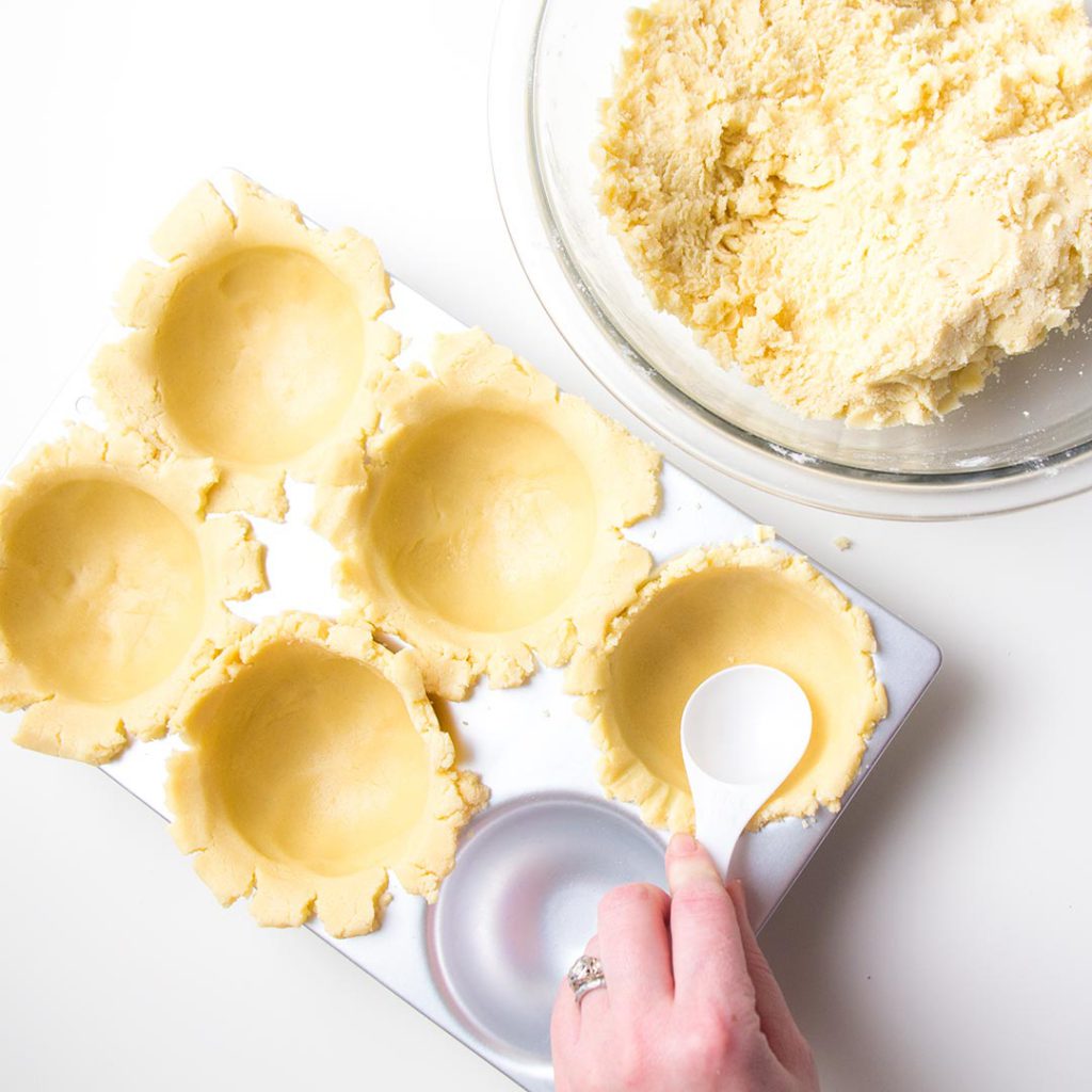 pressing cookie dough into a ball pan 