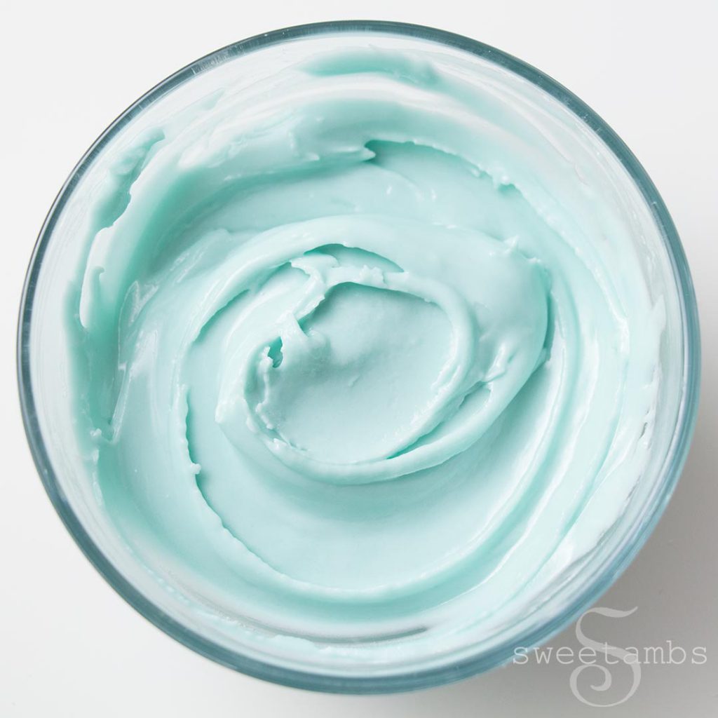 a bowl with light teal royal icing with a spatula swirl