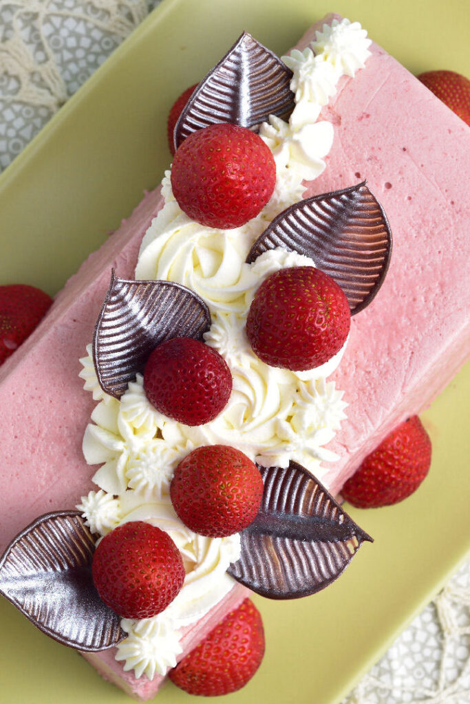 Strawberry mousse icebox cake with chocolate decorations, whipped cream, and fresh strawberries