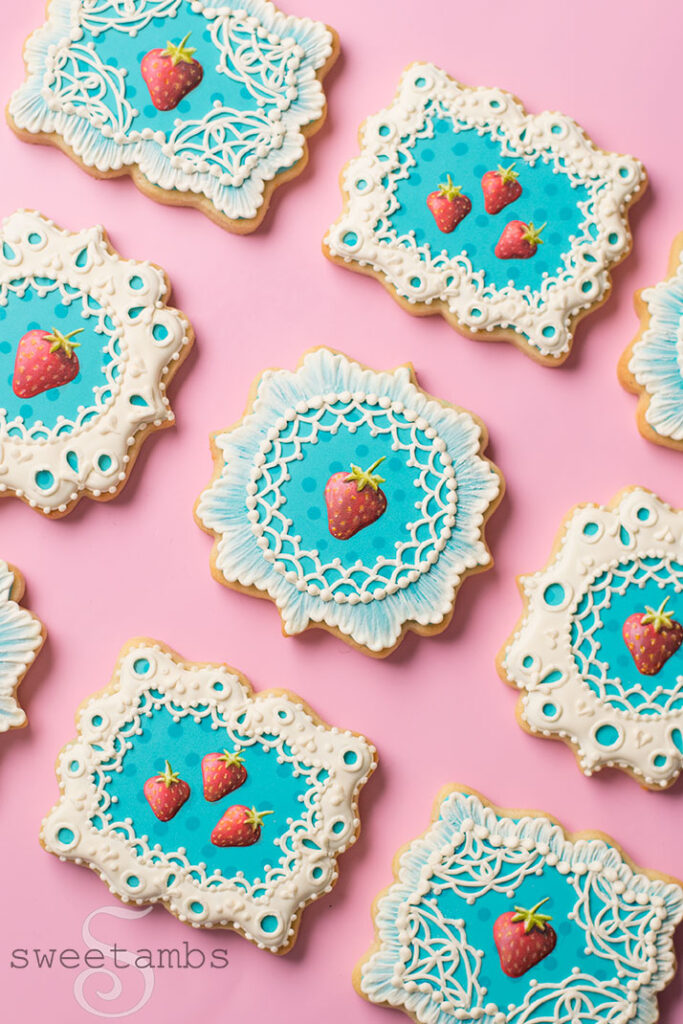 Cookies decorated with royal icing strawberries and eyelet lace.
