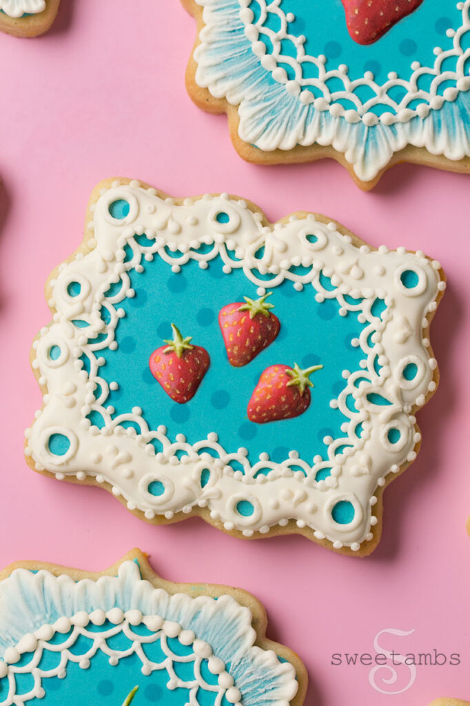 Cookies decorated with royal icing strawberries and eyelet lace.