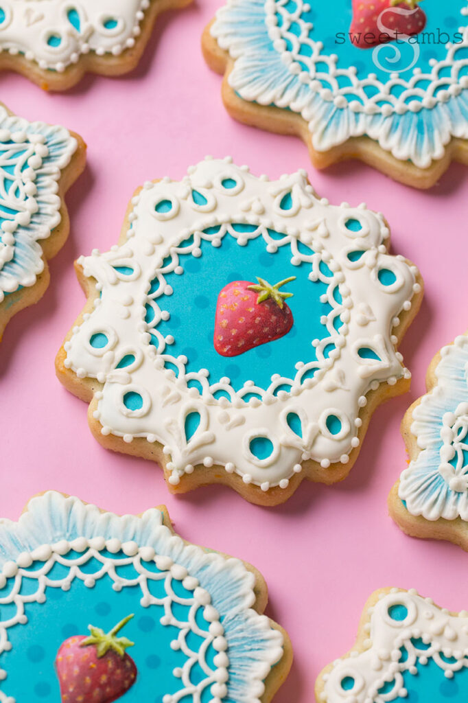 Cookies decorated with royal icing strawberries and eyelet lace.