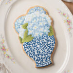 Cookie on a platter decorated to look like a ginger jar with a bouquet of hydrangeas