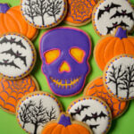 A glowing skull cookie surrounded by cookies decorated with bats, spooky trees, and pumpkins.