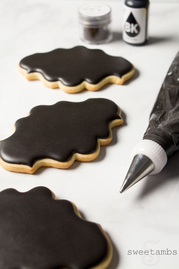 cookies decorated with black royal icing using liquid and powdered food coloring