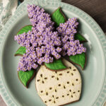 Cookies on a platter decorated to look like lilacs and an eyelet lace vase.
