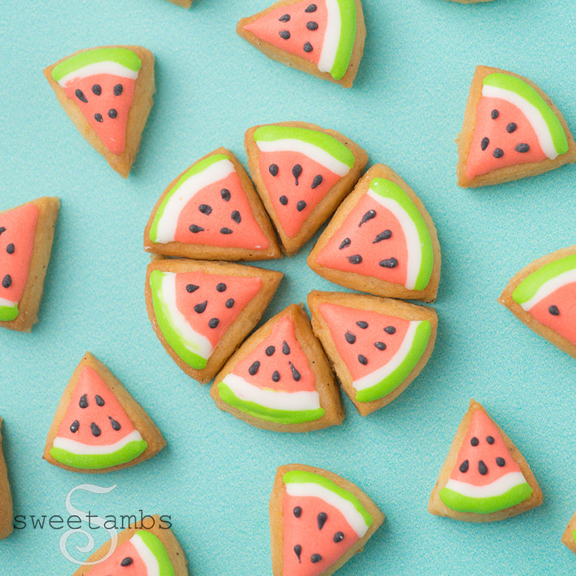 Tiny watermelon slice cookies arranged to form a circle surrounded by scattered watermelon slice cookies.
