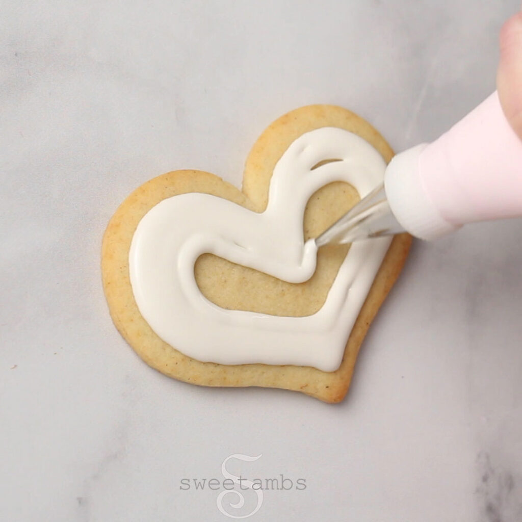 ice a cookie with flood consistency royal icing and a decorating tip 3