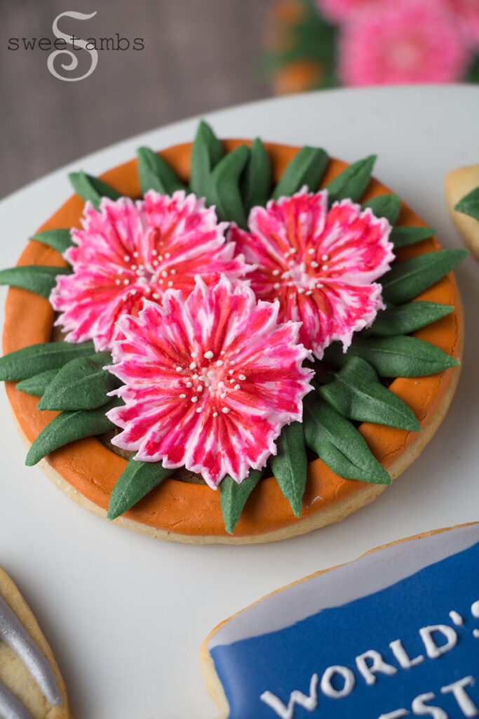A cookie decorated to look like the top view of a flower pot filled with dianthus. 