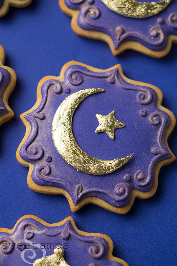Ornate plaque shaped cookie decorated with deep purple icing. The cookie is adorned with a gold crescent moon and star. The edges of the cookie are decorated with a filigree design and gold luster dust.