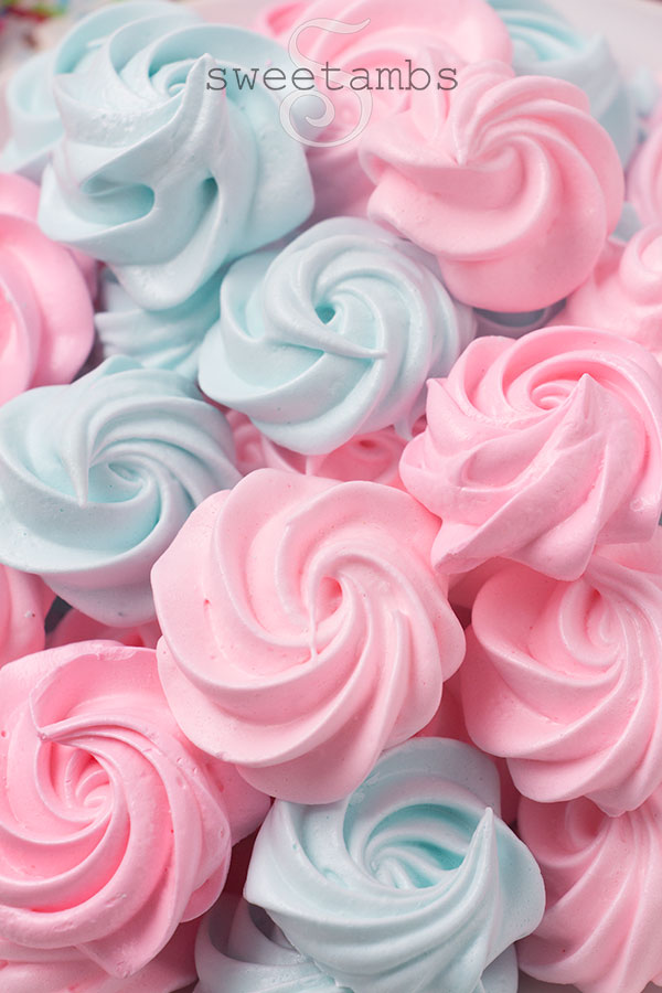 A pile of pink and blue meringue cookies shaped like rosettes