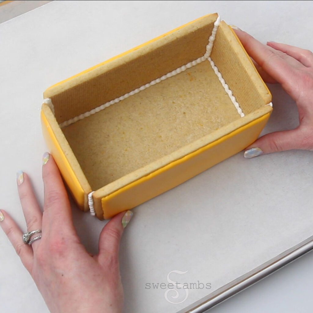 Two hands are holding the sides of the cookie box together. 