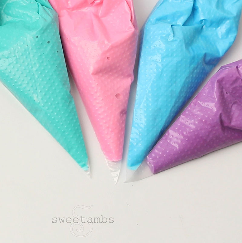 tipless decorating bags filled with teal, pink, blue, and purple royal icing