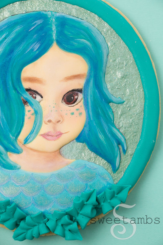 A portrait cookie of a small child decorated to look like a sea creature inspired by the movie Luca