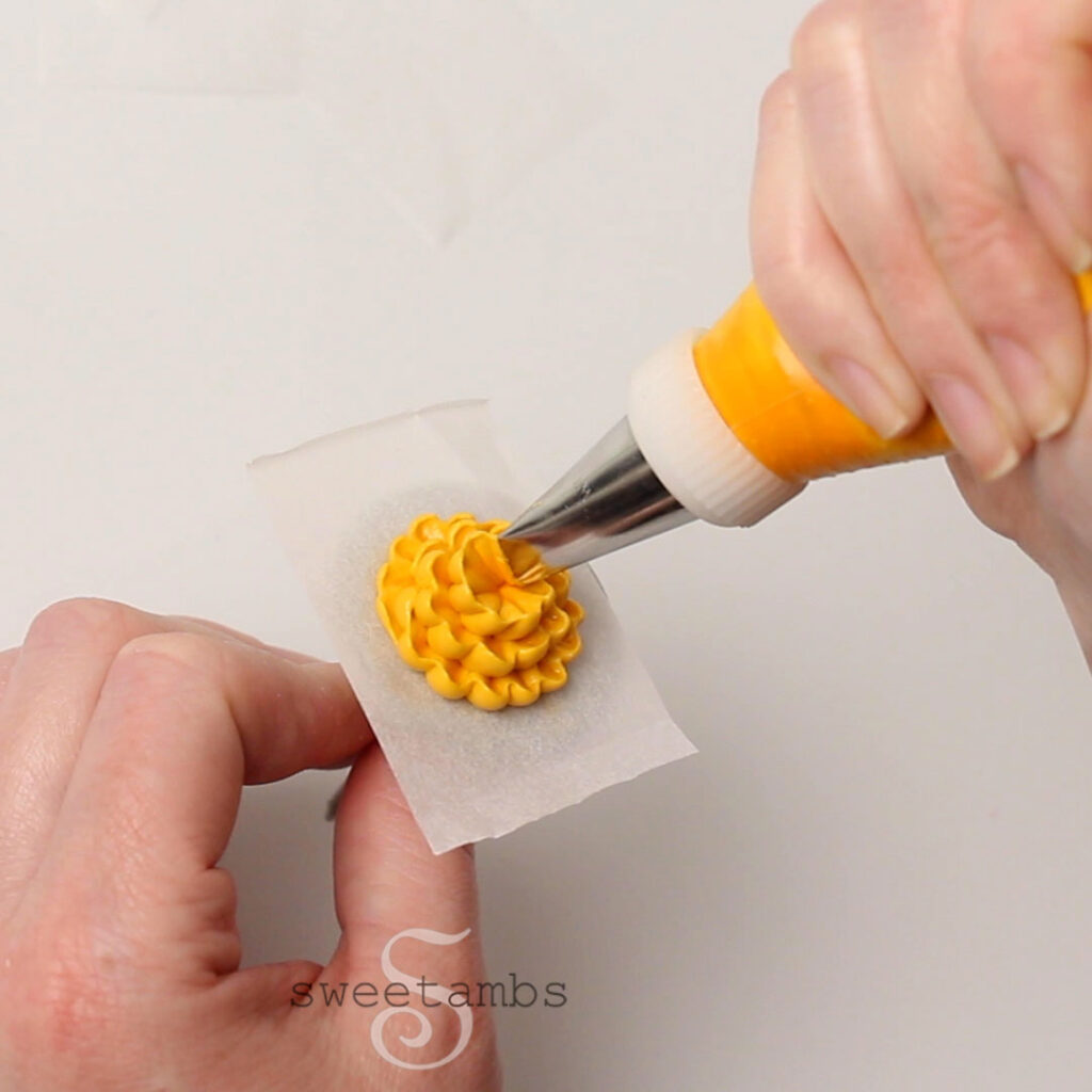 Een goudgele chrysant op een perkamentpapiervierkant steken. 