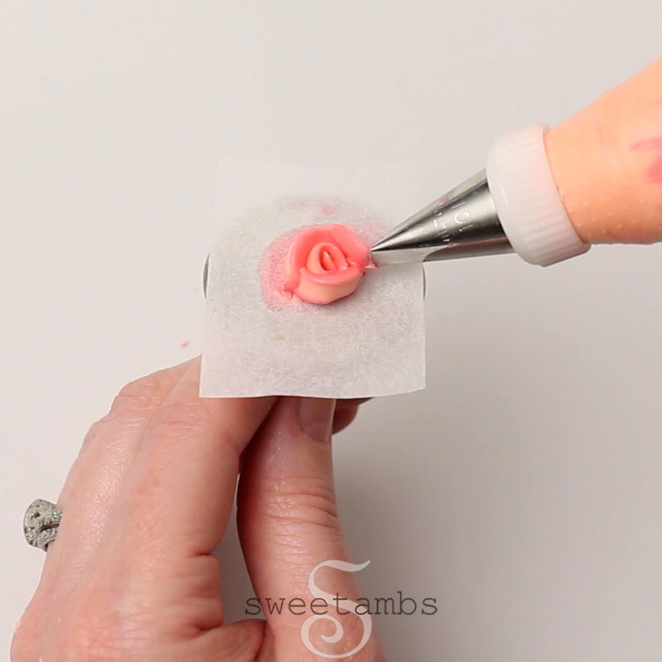Een roze roos op een vierkant van perkamentpapier.