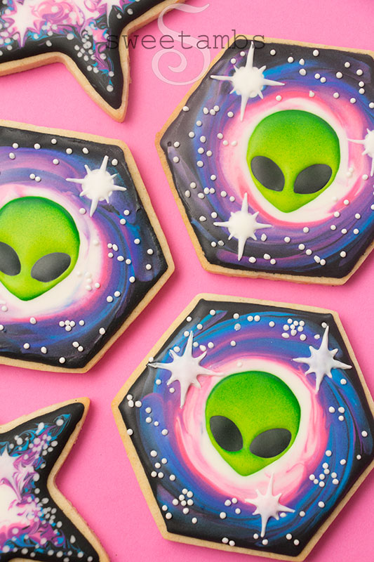 3 hexagon shaped cookies decorated with royal icing aliens and a galaxy design