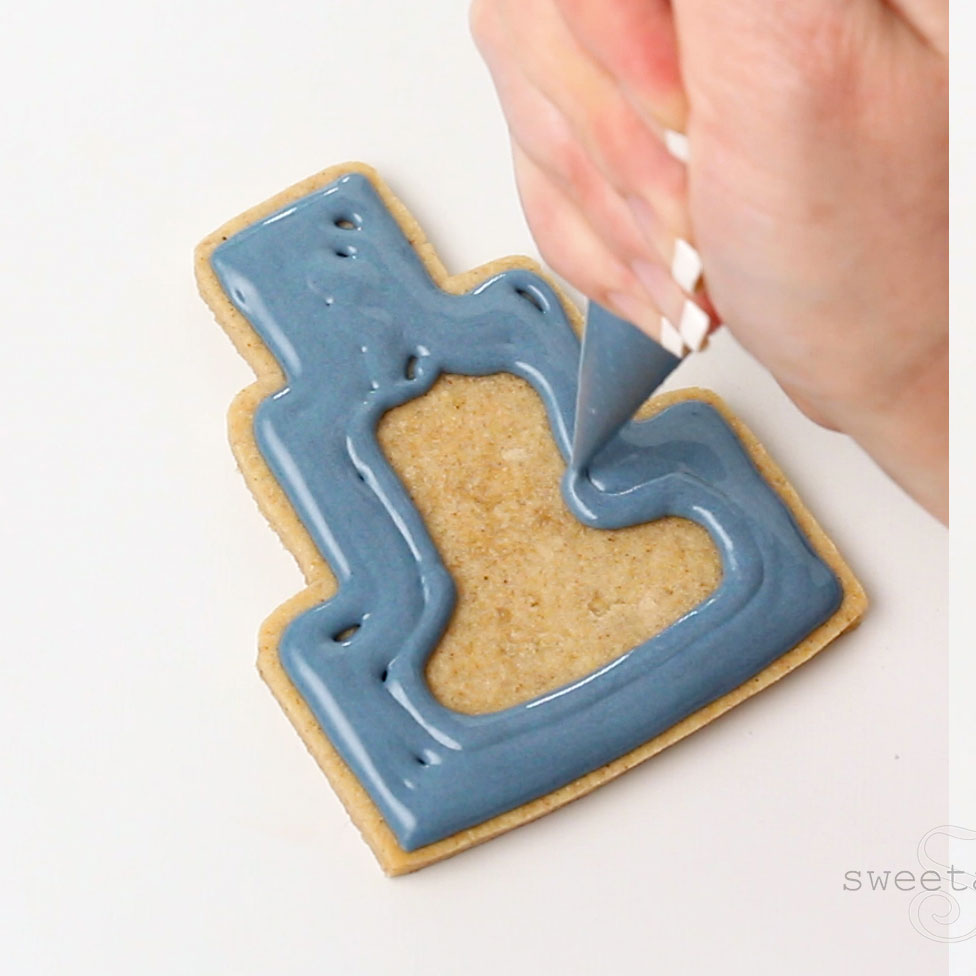 Flooding a tiered cake shaped cookie with dark blue icing