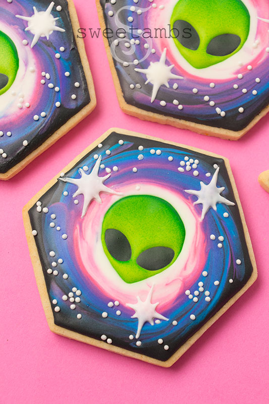 3 hexagon shaped cookies decorated with royal icing aliens and a galaxy design