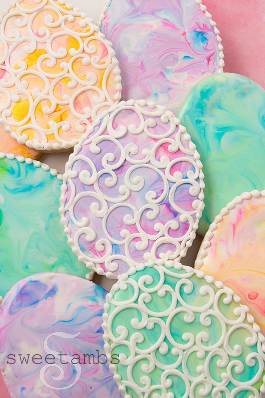 Easter egg cookies decorated with pastel marbled royal icing and white filigree