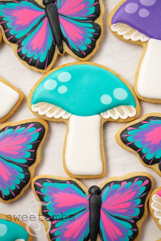 A decorated mushroom cookie surrounded by decorated butterfly cookies
