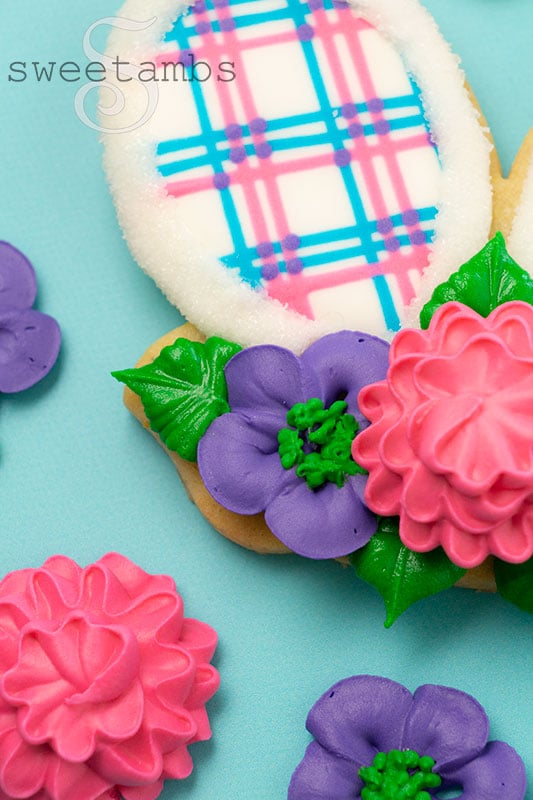 A close up of royal icing flowers on a plaid bunny ear cookie