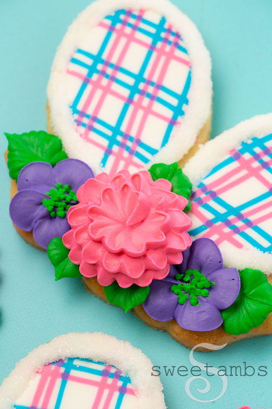A close up of royal icing flowers on a plaid bunny ear cookie