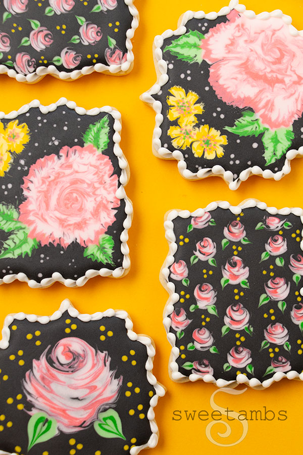 a set of plaque cookies decorated with pink and yellow flowers on black royal icing. The cookies are on a golden yellow background.