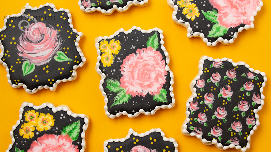 a set of plaque cookies decorated with pink and yellow flowers on black royal icing. The cookies are on a golden yellow background.