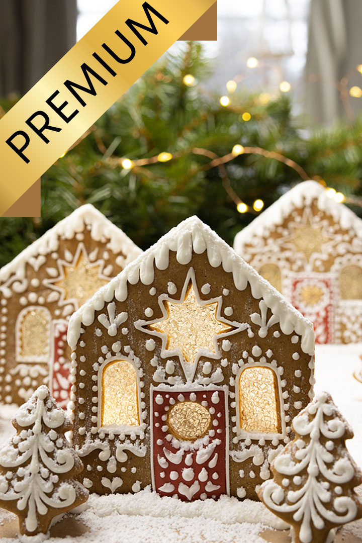 cookies decorated to look like a gingerbread village with frosted glass windows, a red door, and gingerbread Christmas trees