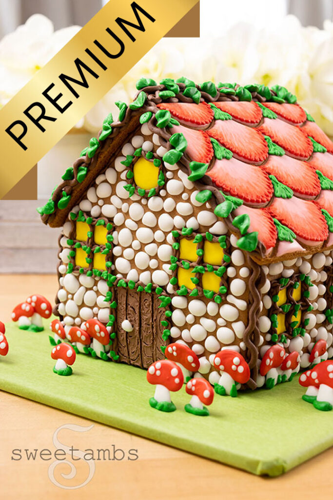 a gingerbread house decorated with royal icing stones, vines, mushrooms, and flower petals. There is a gold banner with the word premium on the top of the photo