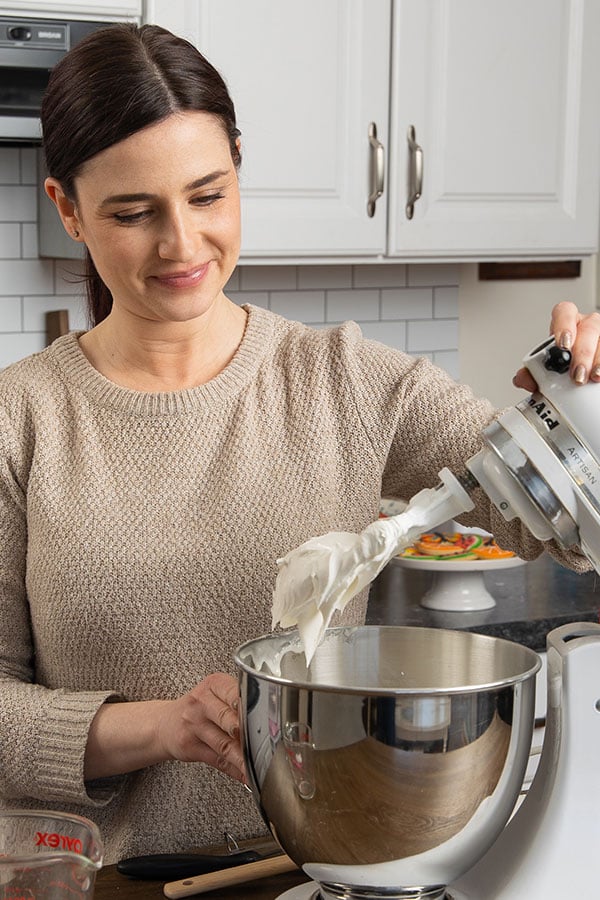 Amber is in the kitchen looking into the bowl of a stand mixer