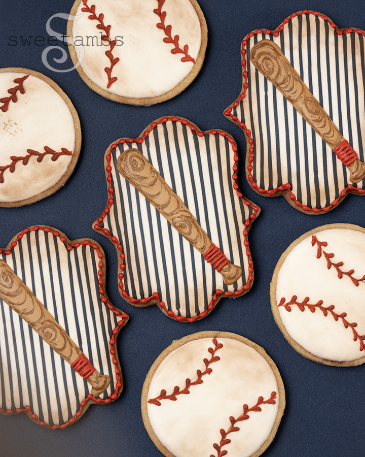 3 plaque cookies decorated with vertical pinstripes and a baseball bat. The plaque cookies are surrounded by baseball cookies. All of the cookies are dusted with brown to give them a vintage look.