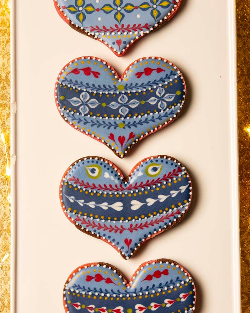 heart shaped cookies decorated in shades of blue with accents of yellow, green, and red.