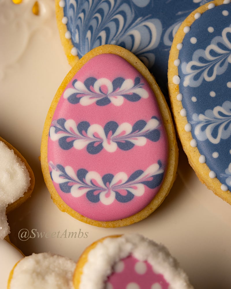 A decorated Easter egg cookie surrounded by other Easter decorated cookies on a platter.