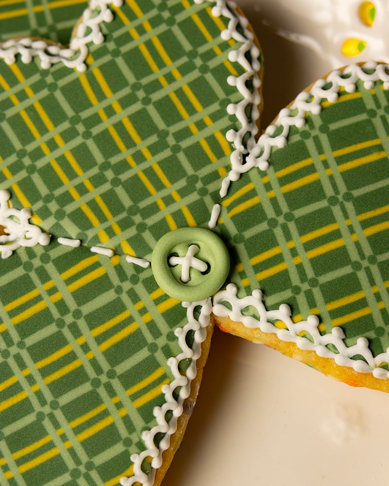 A close up of the button and stitching detail on the plaid royal icing shamrock cookies.