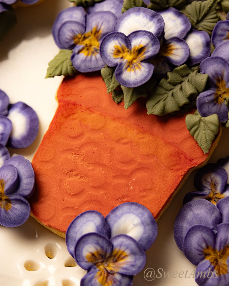 A close up of the potted violas cookie showing the detail of the textured terra cotta royal icing. 