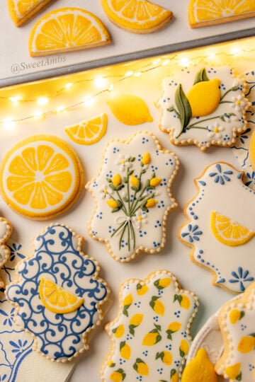 A set of cookies in plaque shapes, circles, and semi circles decorated with royal icing with a lemon theme.