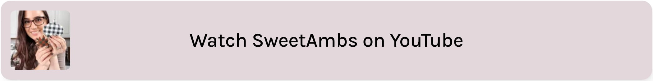 A taupe text box that reads "Watch SweetAmbs on YouTube". there is an image of Amber Spiegel of SweetAmbs holding decorated cookies to the left of the text.